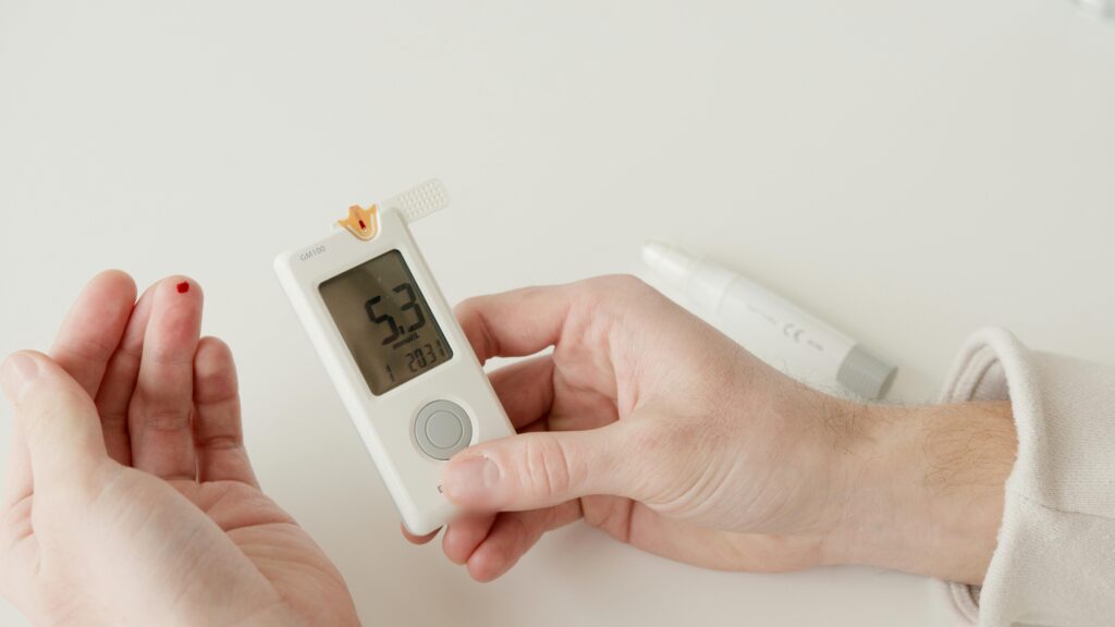 pexels-photo-6823509-6823509 A close-up photo showing a glucometer and a hand pricking to measure blood sugar levels.