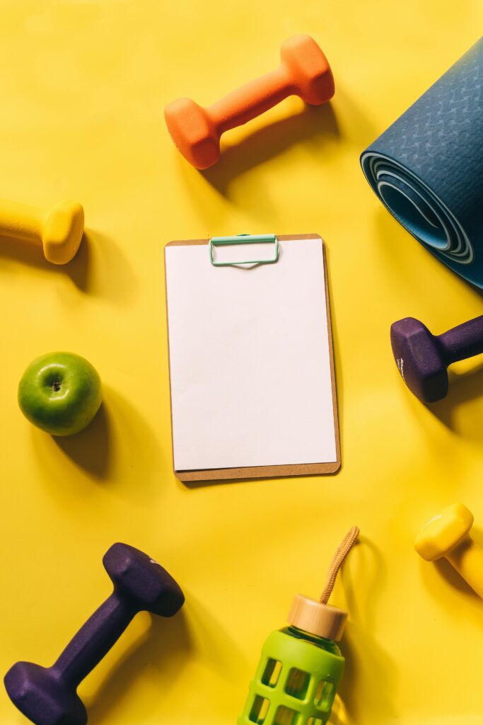 pexels-photo-8154202-8154202 Top view of colorful fitness gear and clipboard on yellow background.